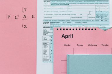 Tax-related items on a pink background, including forms and a calendar.